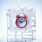 Red alarm clock in a piece of ice